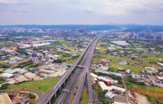 Aerial view of cars driving on highway junctions. Bridge roads with green garden and trees in connection of architecture concept. Top view. Urban city, Taipei, Taiwan.