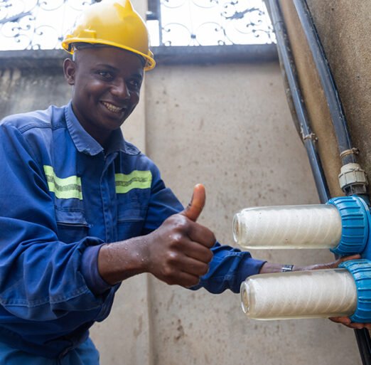Thumbs up of a smiling African plumber, proud to have changed the water filters.